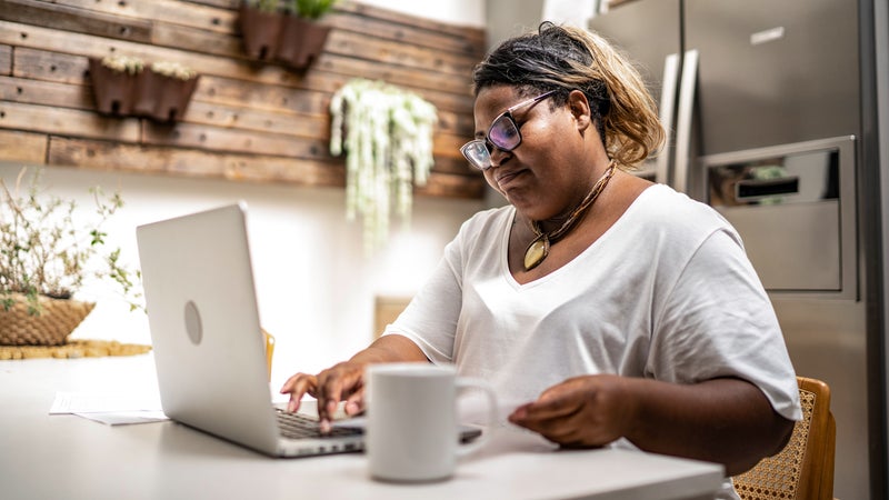 woman working on her laptop at the kitchen table