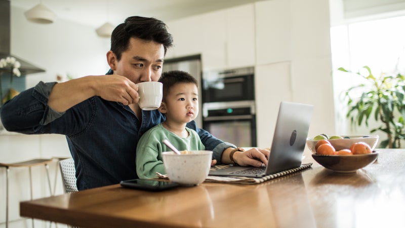 A father multi-tasks with his young son.