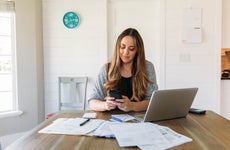 a women on her phone sitting at a table as she presumably goes through her account