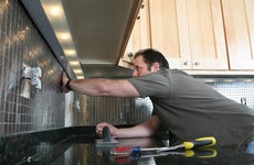 A contractor installs backsplash in a kitchen